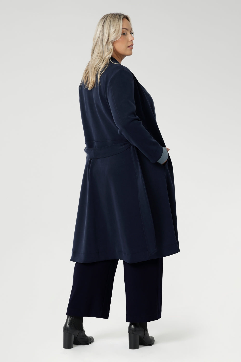 The coat features tailored panels at the front with concealed pockets seamlessly integrated into the seams, along with two-piece long sleeves for a refined fit.