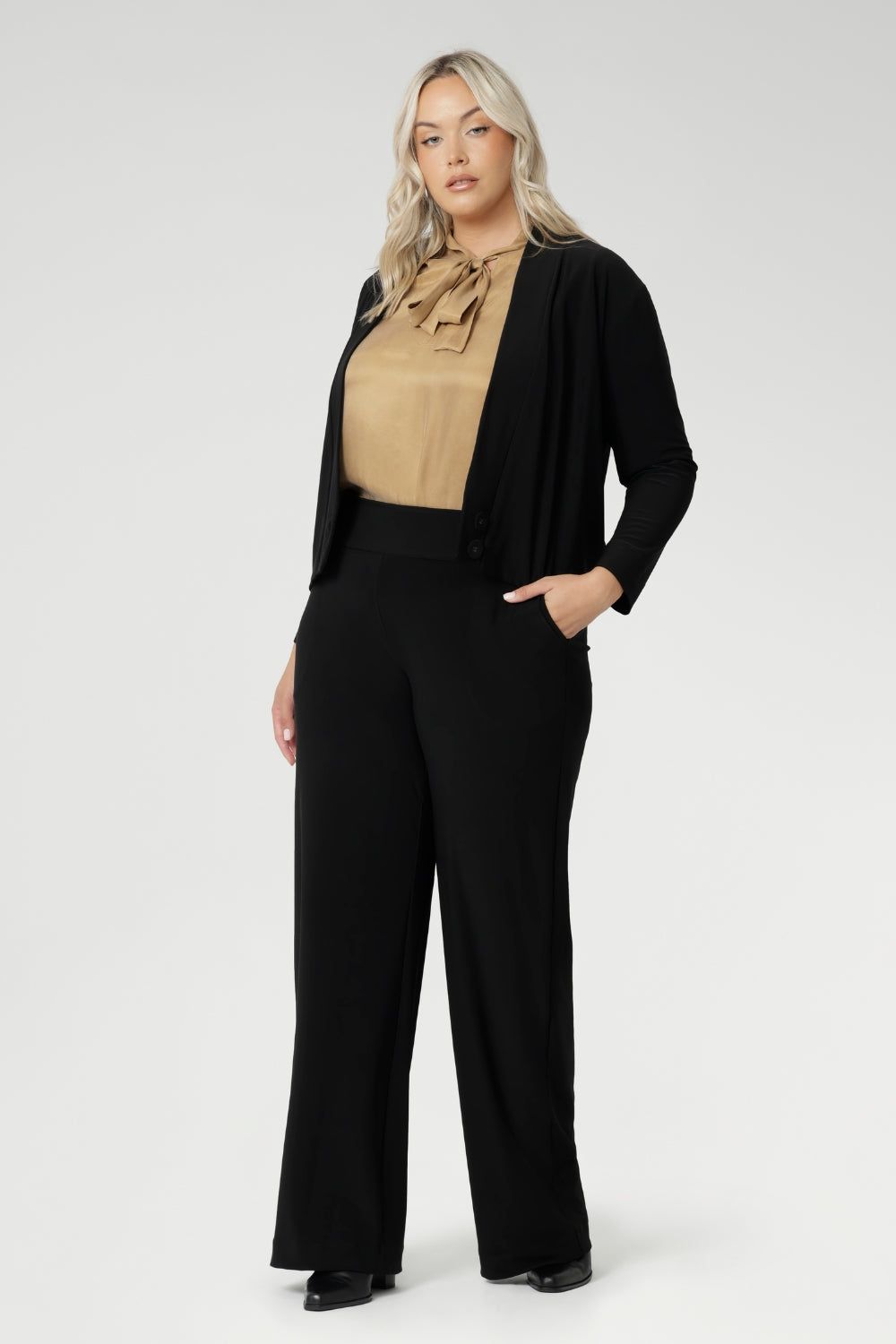 Size 18 woman wears black Jacardi, which is part jacket, part cardigan. This soft touch jacket is a transeasonal cover up. Featuring V-neckline, long sleeves and front buttons. This casual black jacket is made from stretchy and comfortable jersey fabric. Easy care workwear jacket available in sizes 8-24.