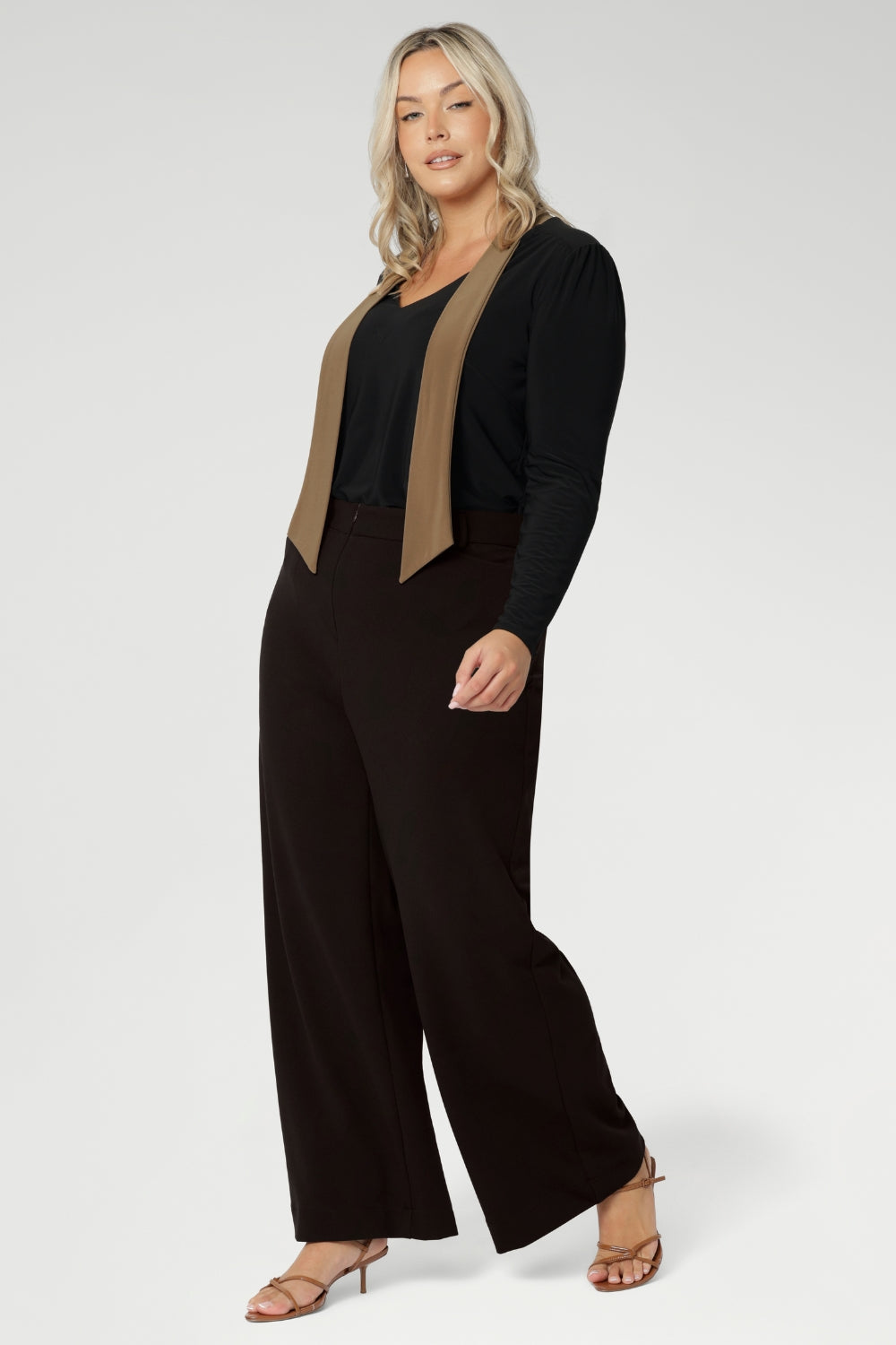 Plus size woman wears woman's easy care top that features neck ties and long sleeves, tucked into her brown high waisted pants. Crafted from our signature dry touch, wrinkle-resistant jersey fabric with an easy care finish that makes it perfect for regular wear.