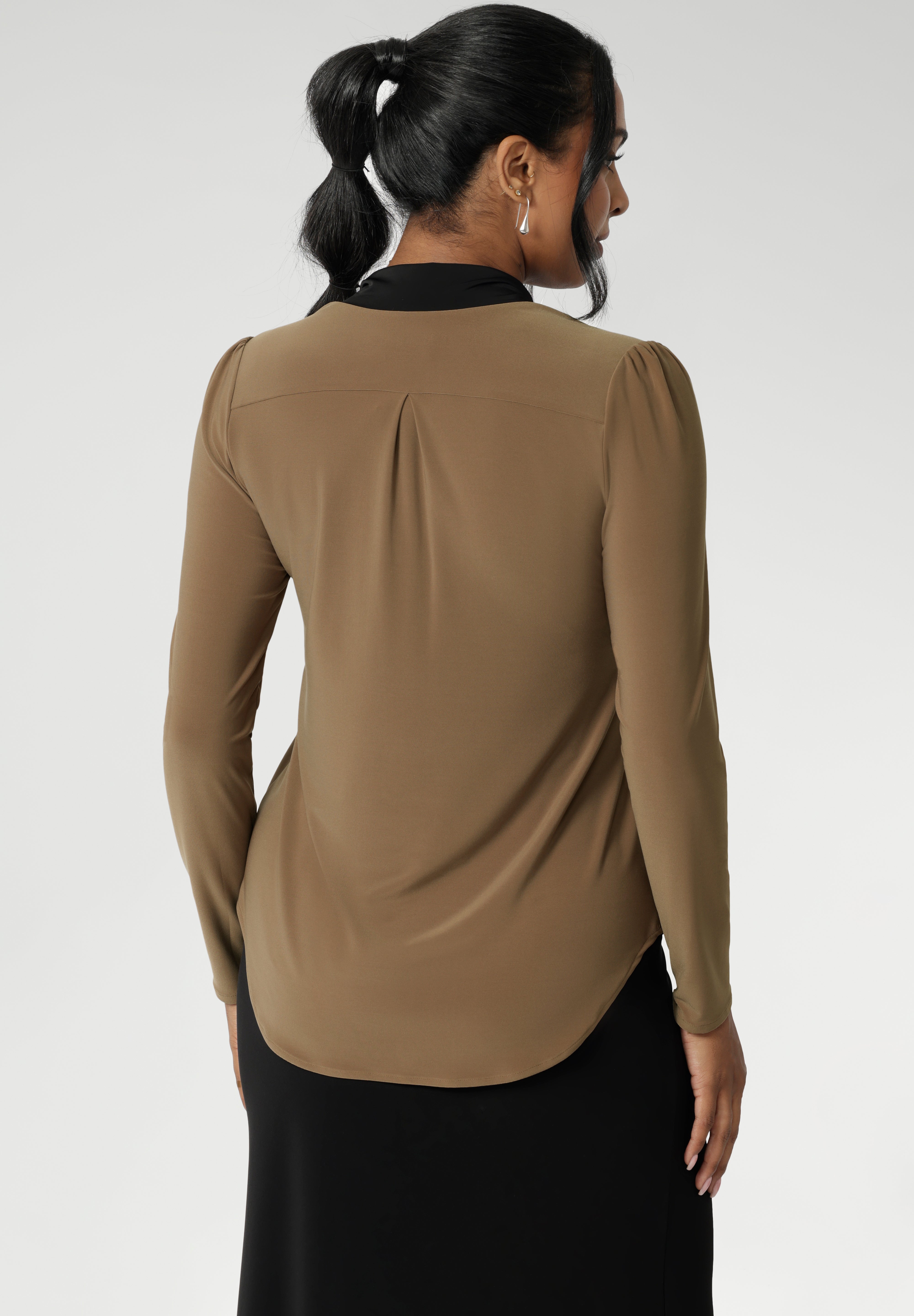 Full-length sleeves with gentle gathers at the shoulders add a touch of femininity, while the shoulder yoke and tailored tuck at the back create subtle shape without feeling structured. Finished with a shirttail hemline, it’s a top that layers easily under suiting and transitions seamlessly from desk to dinner.