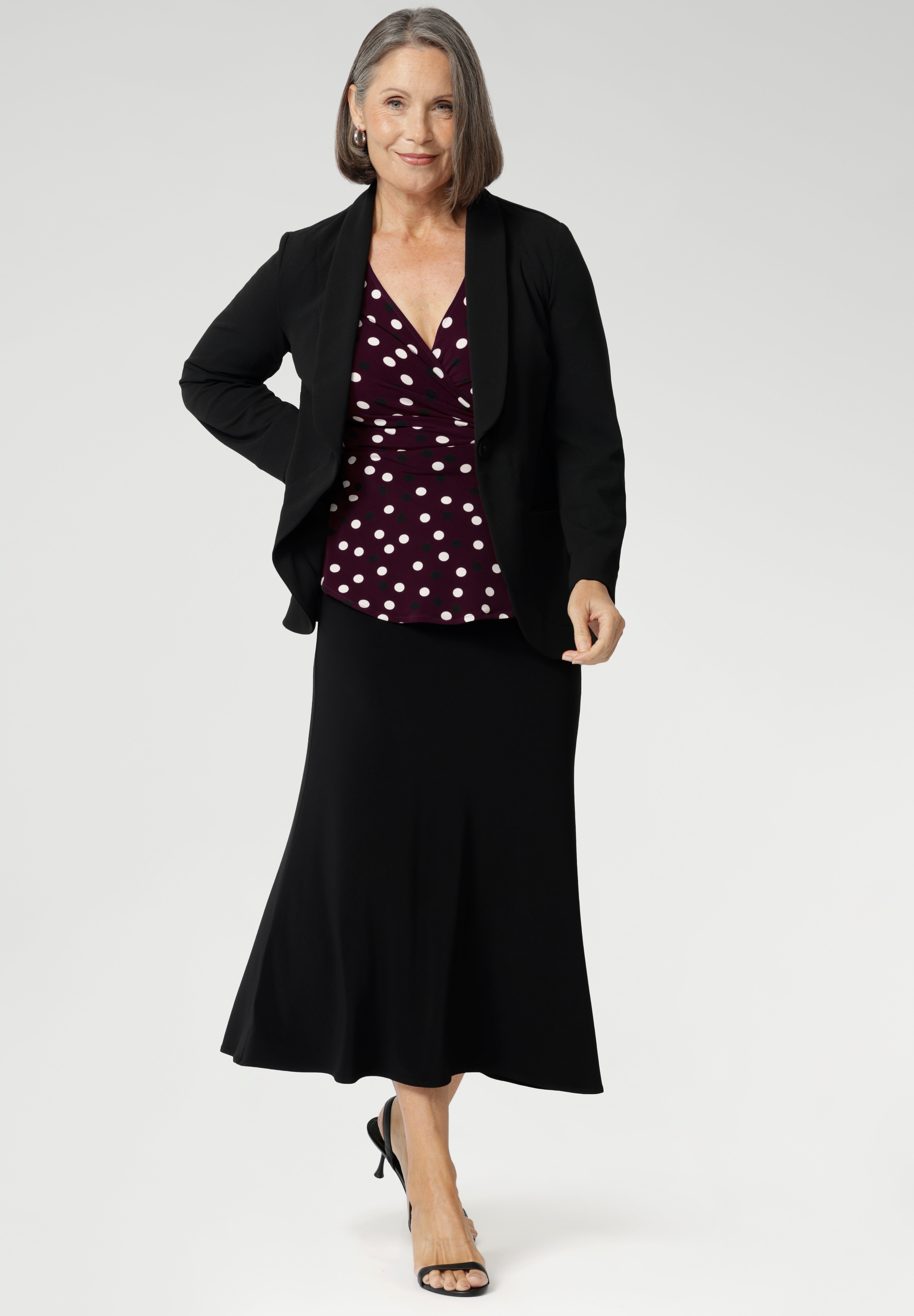 Our mature-aged model wears this elegant women’s workwear top, designed with a flattering peplum silhouette and a dipped back hem for added coverage and a feminine finish. Proudly Australian made from a dry-touch jersey fabric, this style is available in sizes 8–24. Style with Merit Blazer in Black & Asher Skirt in Black.