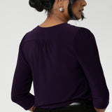 Close up image of Amethyst coloured woman's workwear shirt displays the tailored details such as centre-back gathers and shoulder tucks. Size 10 woman workwear shirt is worn tucked into black tailored pants with belt loops.