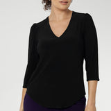 Size 10 woman wearing the Vida top in black that has a V-neckline and 3/4 sleeve. Comfortable dry touch jersey top for corporate workwear to weekend. Made in Australia for women sizes 8-24.