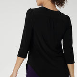 Size 10 woman wearing the Vida top in black that has a V-neckline and 3/4 sleeve. Comfortable dry touch jersey top for corporate workwear to weekend. Made in Australia for women sizes 8-24.