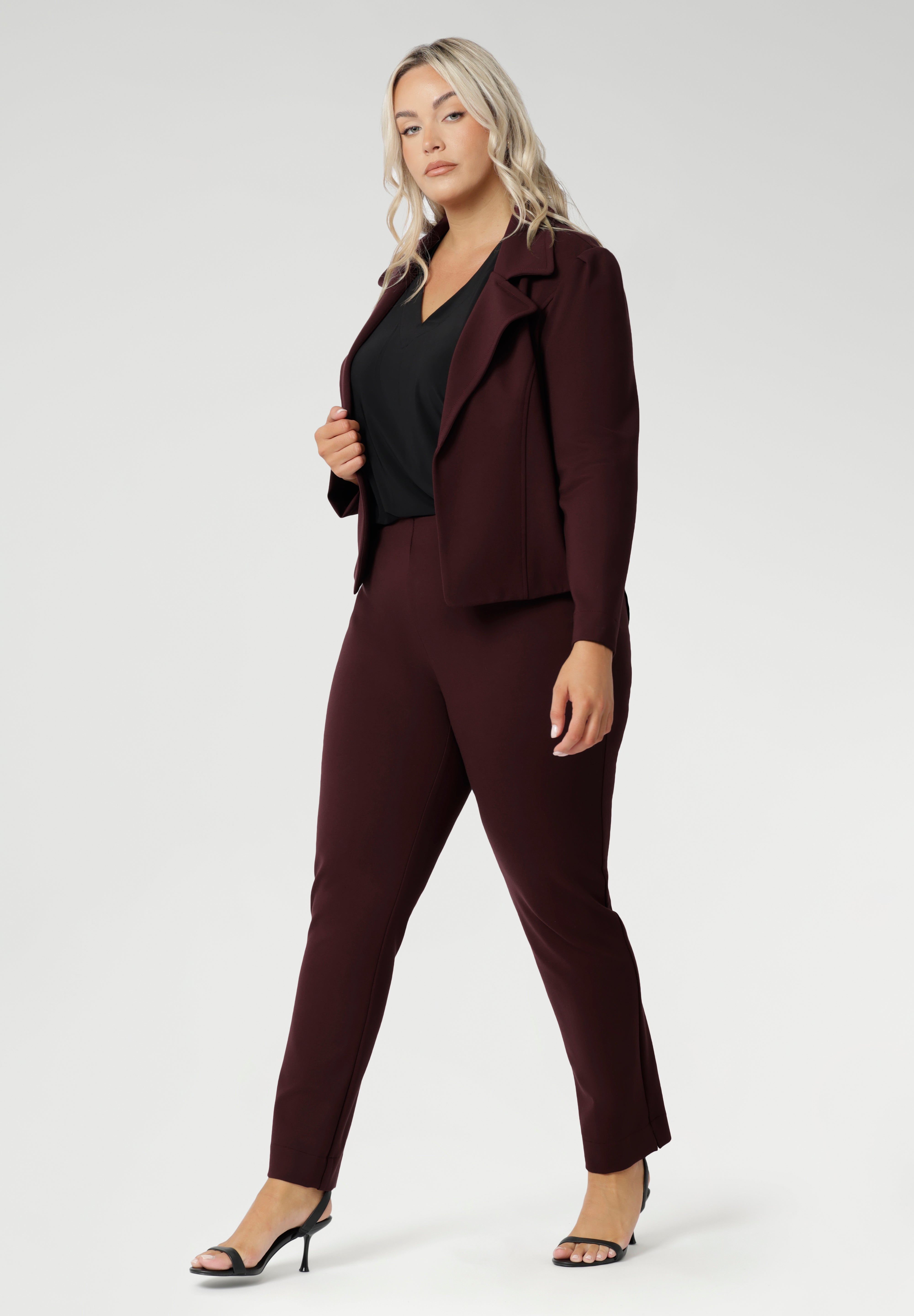Plus size woman wears the Vida top in black that has a V-neckline and 3/4 sleeve with burgundy suiting set, with matching pants and jacket. Comfortable dry touch jersey top for corporate workwear to weekend wear. Made in Australia for women sizes 8-24.