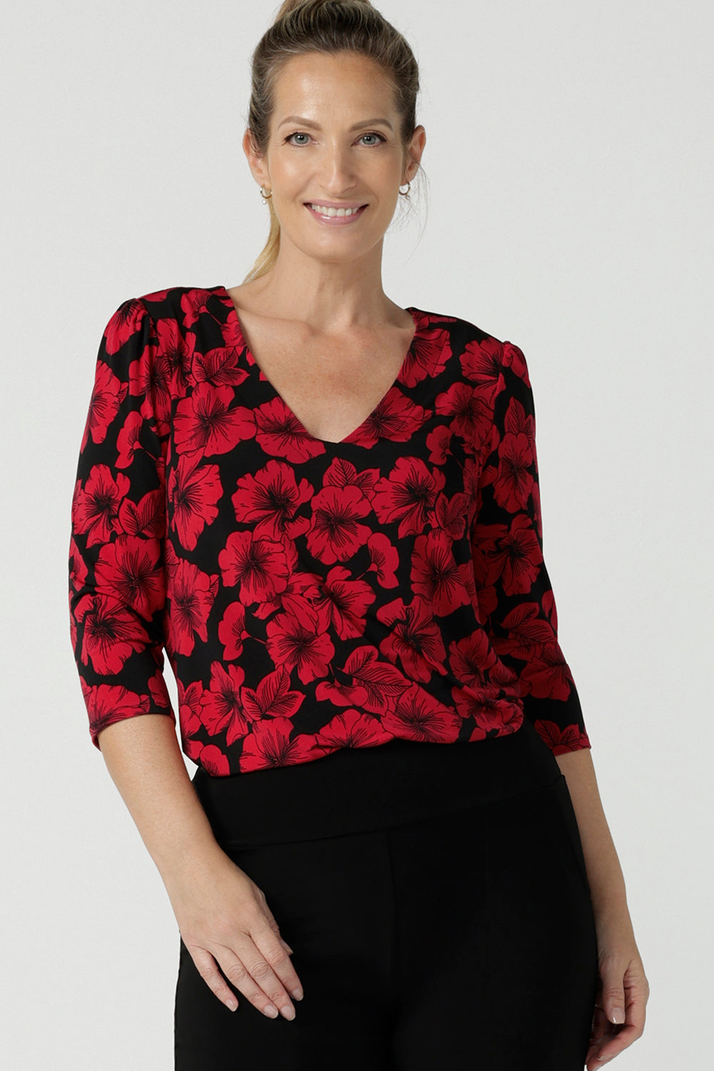 Size 10 woman wears the Vida Top with a v-neck and bold poppy floral. Comfortable workwear top for women size 8 - 24. Black base with a red flower. Versatile and comfortable workwear. Styled back with a black slim Andi tube skirt. Made in Australia for women.