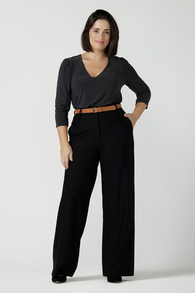 A size 10 woman wears the Kade pant in black, a softly tailored black pant in ponte jersey. Functioning fly front, belt loops, side pockets and a straight let. Made in Australia for women size 8 - 14. Styled back with the Vida top in charcoal 3/4 sleeves and a v-neckline. 
