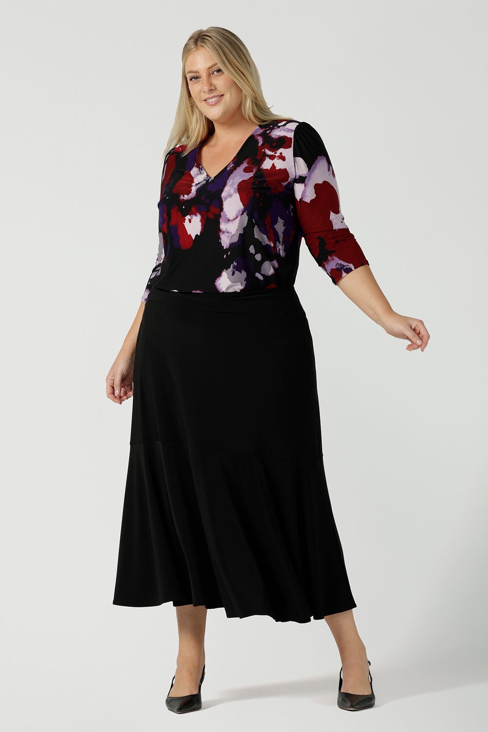 A size 18 woman wears the Vida top in Fitzroy with a V-neckline and 3/4 sleeve. Curved hemline and comfortable workwear for women made in Australia for women size 8 to 24.