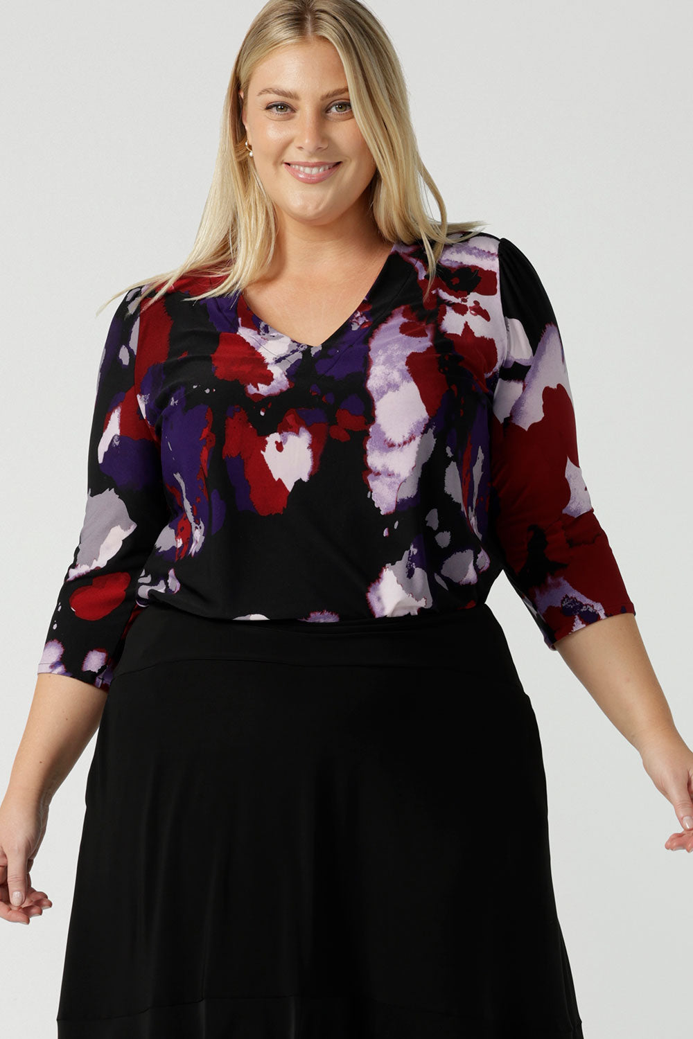 Close up of a size 18 woman wears the Vida top in Fitzroy with a V-neckline and 3/4 sleeve. Curved hemline and comfortable workwear for women made in Australia for women size 8 to 24.