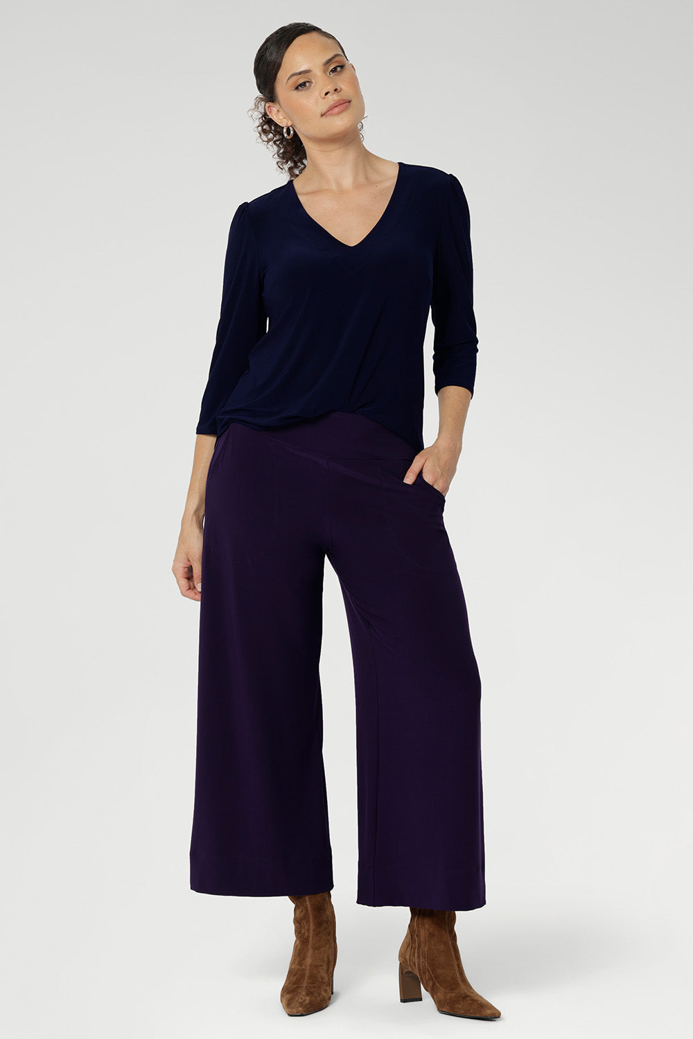 Woman wears the Vida Top in classic Navy, showcasing its flattering V-neckline and elegant 3/4 sleeves. Crafted from our signature dry-touch stretch jersey, this top offers all-day comfort and effortless style.