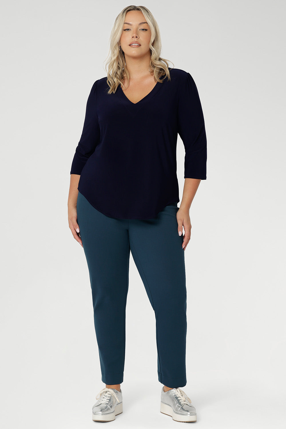 A plus-size model wears the Vida Top in timeless Navy, featuring a flattering V-neckline and 3/4 sleeves that offer the perfect balance of coverage and style. Made from our signature dry-touch stretch jersey, this top delivers exceptional comfort and a polished look.