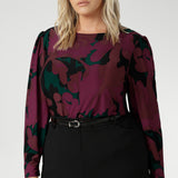 The Fuchsia Maya print is on a soft touch jersey fabric with print details in deep fuchsia, green, terracotta and black. The fabric has soft stretch. Plus size model wears her long sleeved top tucked into black workwear skirt. Available in sizes 8-24.