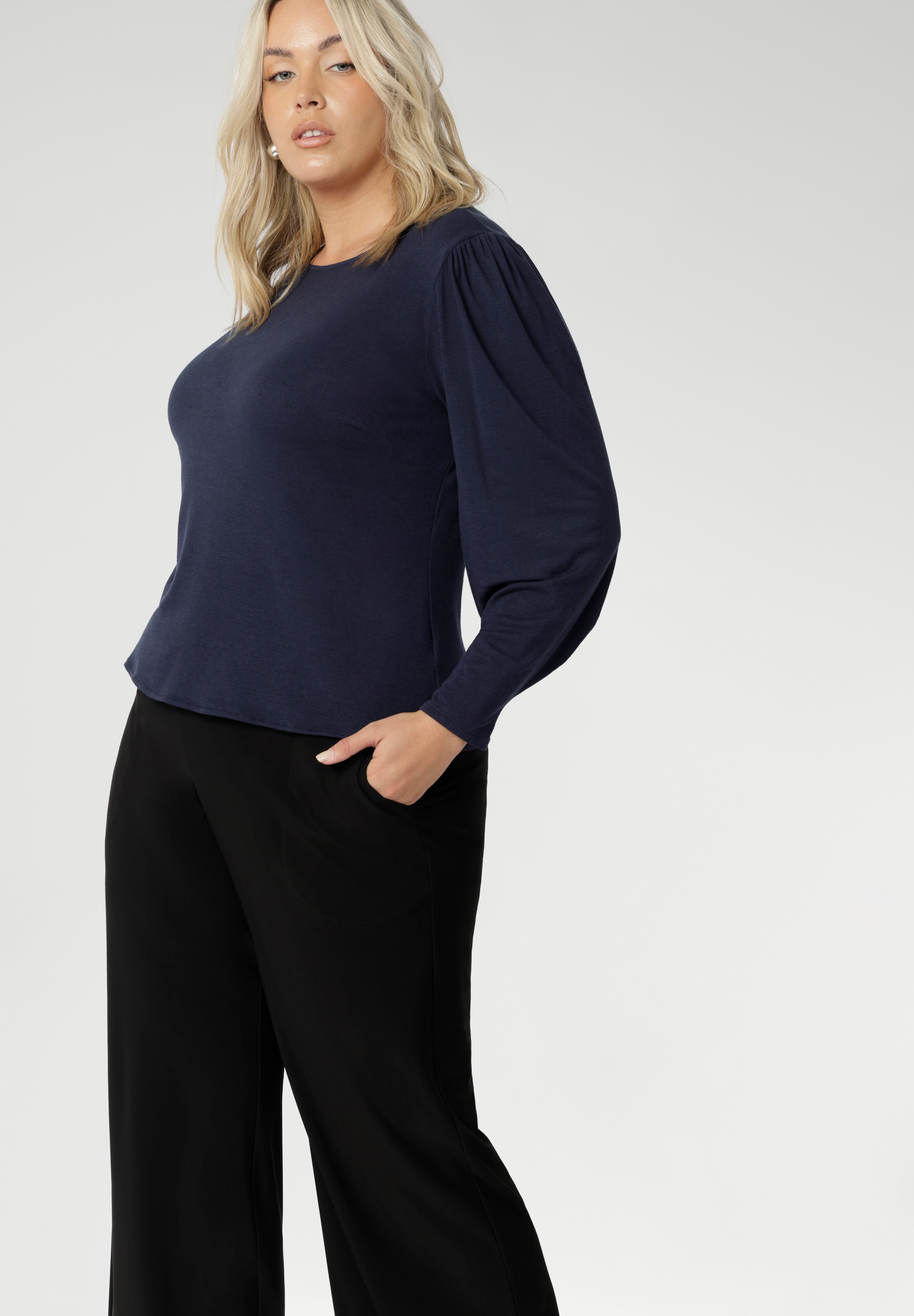 Feminine cut knit top features a boat neckline and full-length bellow sleeves with soft gathers at the shoulders and tailored darts at the wrists, adding gentle volume without the bulk. Subtle shaping through the body and bust darts create a flattering, close-to-body fit that moves easily from work to weekend. Available in sizes 8-24.