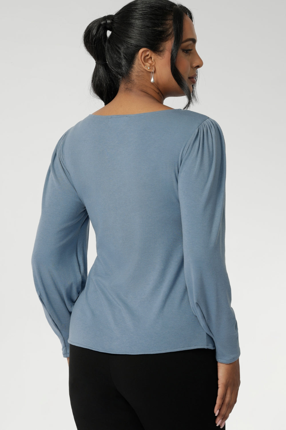 The boat neckline frames the collarbone with subtle sophistication, while tailored bust darts and a close-to-body shape enhance the fit without feeling restrictive. Crafted with attention to detail, the full-length sleeves feature gentle gathers at the shoulder and a wrist dart, adding soft volume and movement—ideal for styling under outerwear without bulk.