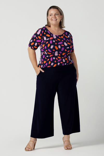 Size 18 curvy woman wears the Ziggy top in Palette. A boat neckline style with short sleeves and shoulder tucks. A great work to weekend top for women. Palette print features a brush stroke print of fuchsia, lilac, red and orange . Made in Australia for women size 8 to 24.Styled back with Bradley culottes in Navy.