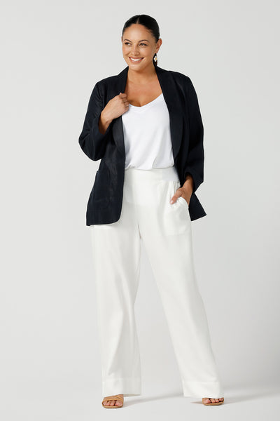 A size 12, curvy woman wears a tailored linen, boyfriend blazer in midnight blue with white pants and white bamboo jersey cami top - great for summer capsule wardrobes and travel wear! Both are made in Australia by Australian and New Zealand women's clothing brand, Leina & Fleur. 