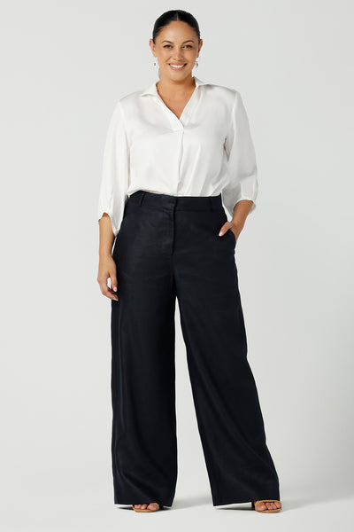 A size 12, curvy woman wears tailored linen, wide leg pants in midnight blue with a white shirt in tencel fabric - great for women's workwear! Both are made in Australia by Australian and New Zealand women's clothing brand, Leina & Fleur. 