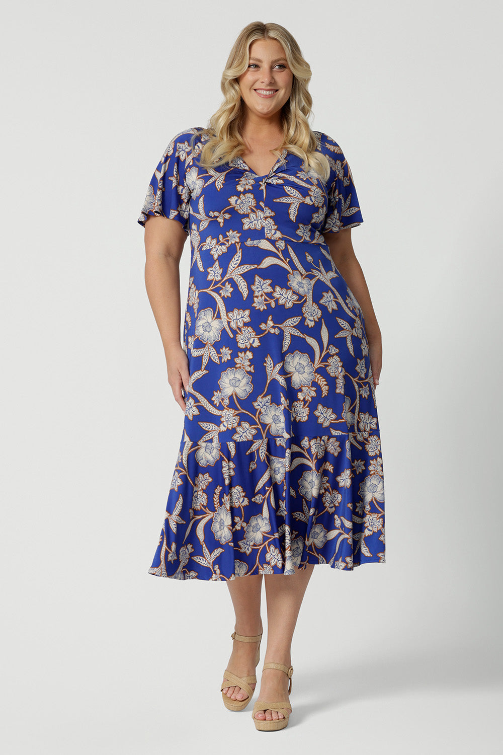 Showing a good empire line dress for  plus size women, this twist front jersey dress in size 18 has flutter sleeves and a ruffle hem. A blue dress with floral print, be holiday ready with this travel and cruise wear dress style. Made in Australia by Australian and New Zealand women's clothes brand, Leina & Fleur, shop their petite to plus sizes dresses online.