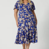 Showing a good empire line dress for  plus size women, this twist front jersey dress in size 18 has flutter sleeves and a ruffle hem. A blue dress with floral print, be holiday ready with this travel and cruise wear dress style. Made in Australia by Australian and New Zealand women's clothes brand, Leina & Fleur, shop their petite to plus sizes dresses online.