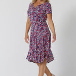 Summer dresses for over 40s women don't get much beter than this! A size 12, over 40 woman wears knee length summer dress with asymmetric hemlineand cowl neck. A short sleeve dress in pretty red, pink, white and navy print this is a good jersey dress for travel and cruise wear.  Shop Australian-made dresses by L&F online as petite to plus size dresses online. 
