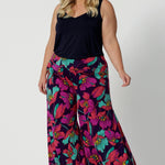 A curvy size 18 woman wears the Caspian Palazzo pant in a bright floral print. In soft and lightweight jersey this pant features side pockets and a flared leg opening. Handmade in Australia in sizes 8-24 by Leina & Fleur.