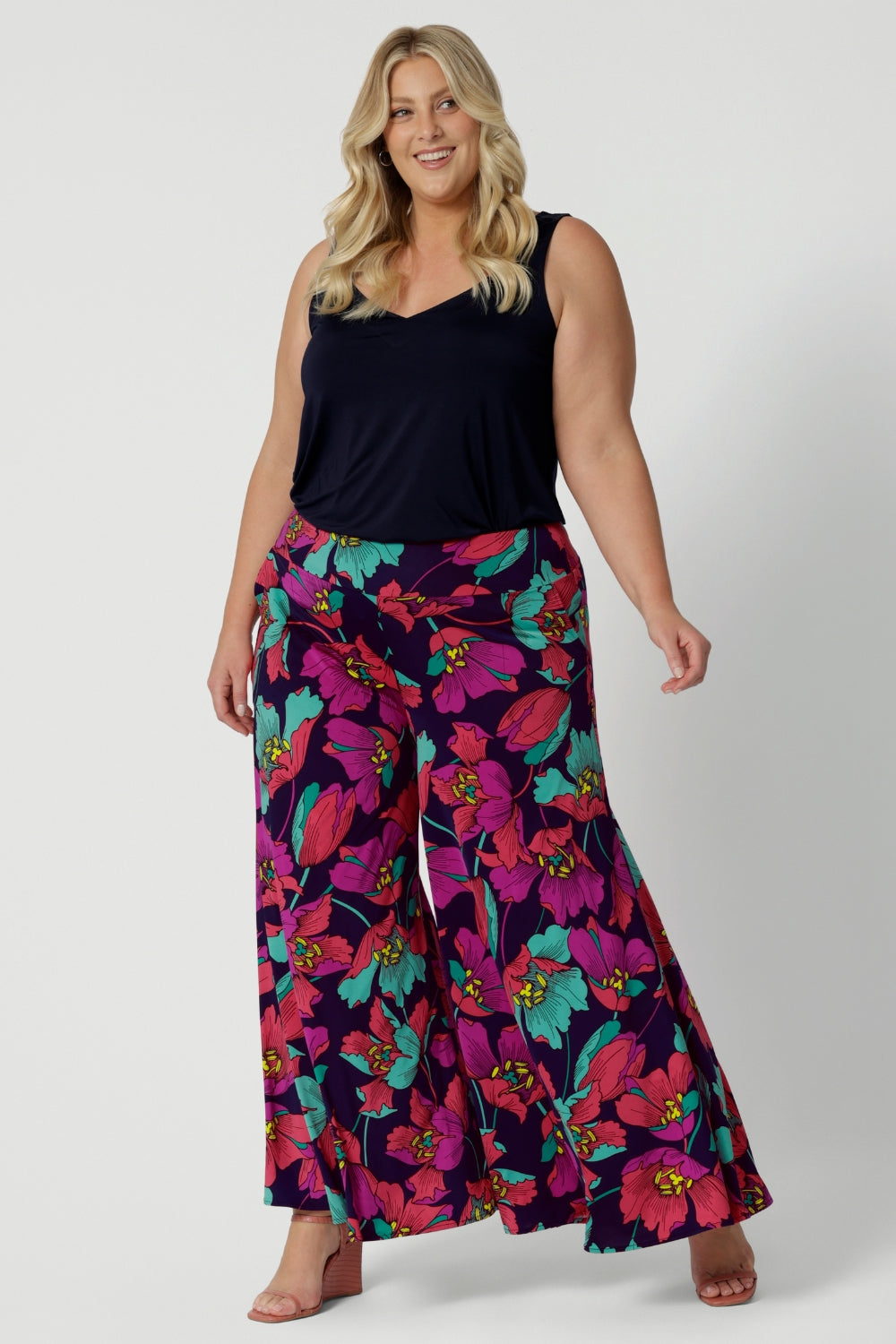 A curvy size 18 woman wears the Caspian Palazzo pant in a bright floral print. In soft and lightweight jersey this pant features side pockets and a flared leg opening. Handmade in Australia in sizes 8-24 by Leina & Fleur.