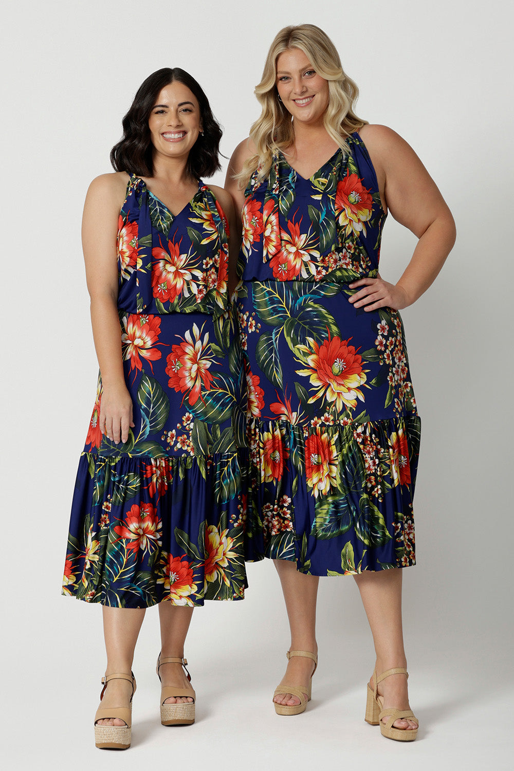 Full body image of two woman of different heights wearing the Darci Knee Length Dress in Bahagia. Floral halter dress is stocked in petite and plus sizes. This resort ready dress is made from slinky jersey fabric.This resort style dress is perfect for travel as the fabric is wrinkle resistant. Leina & Fleur is a woman's brand that stock sizes from 8 to 24.