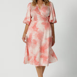 Showing a good dress for over 40s women, this silky wrap dress has an orange spot print and 3/4 lantern-shaped sleeves. Made in Australia by women's clothing brand, Leina & Fleur, wear this 3/4 sleeve wrap dress for wedding guest outfit and summer event  wear. Shop this summer wedding guest and event wear outfit online in sizes 8 to 24.