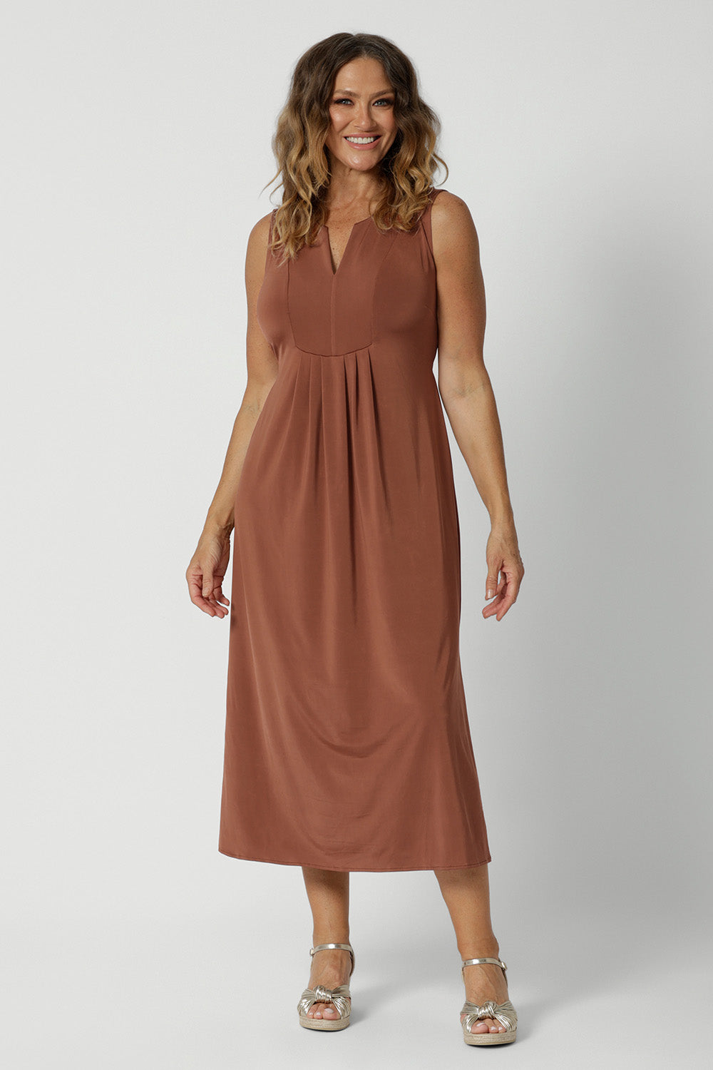 Showing a dress for 0ver 40s women, this sleeveless clay coloured dress in slinky jersey fabric is perfect as an off duty summer dress. Made in Australia by Australian and New Zealand women's clothing brand, Leina & Fleur. This midi-length empire line dress is available in sizes 8 to 24.