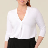 A great top for curvy women, this white bamboo jersey top is tailored with a pleat below the V-neck. Lightweight and breathable, this 3/4 sleeve top makes a comfortable work top, looking classic under workwear jackets and suits. A classic top, this white jersey top is good for casual wear and travel capsule wardrobes too. shown on a curvy, mid size woman, this top is also available in petite and plus sizes online at women's clothing brand, Leina & Fleur. 