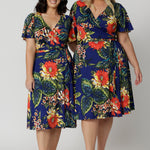 Two women of different heights wearing the Maggie Knee Length Dress in Bahagia. Floral wrap dress is stocked in petite and plus sizes. This resort ready dress is made from blue slinky jersey fabric. This resort style dress is perfect for travel as the fabric is wrinkle resistant and packs well in a suitcase. Leina & Fleur stock many resort style dresses and tops in sizes from 8 to 24.