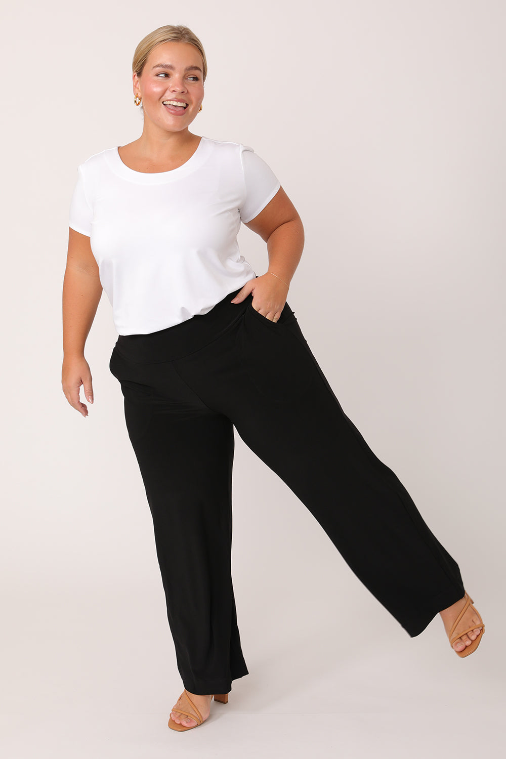A curvy petite height woman wears black work pants in petite length with a white bamboo jersey T-shirt top. Great pants for short women, these black jersey pull-on trousers are available in sizes 8 to 24, petite to plus sizes.