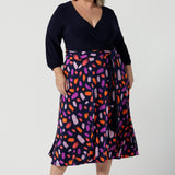 Size 18 curvy woman wears the Nerida dress. Functioning fit and flare wrap dress with a navy bodice and printed skirt. 3/4 Sleeves and functioning pockets. Made in Australia for women. Size 8 - 24. Styled back with a brown sling back heel. 