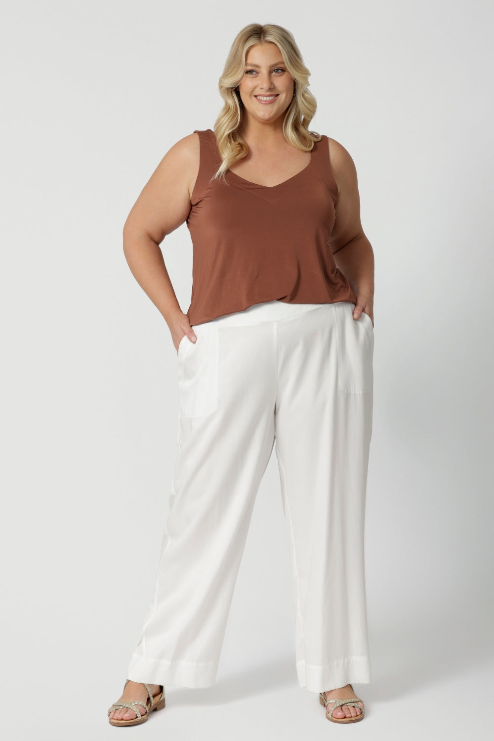 A curvy, size 18 woman wears white wide leg pants. These pull-on, easy care pants are comfortable for your everyday capsule wardrobe. Shop these Australian-made summer ready pants online in sizes 8 to 24. From petite to plus sizes at Leina & Fleur. 