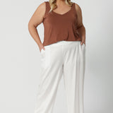 A curvy, size 18 woman wears white wide leg pants. These pull-on, easy care pants are comfortable for your everyday capsule wardrobe. Shop these Australian-made summer ready pants online in sizes 8 to 24. From petite to plus sizes at Leina & Fleur. 