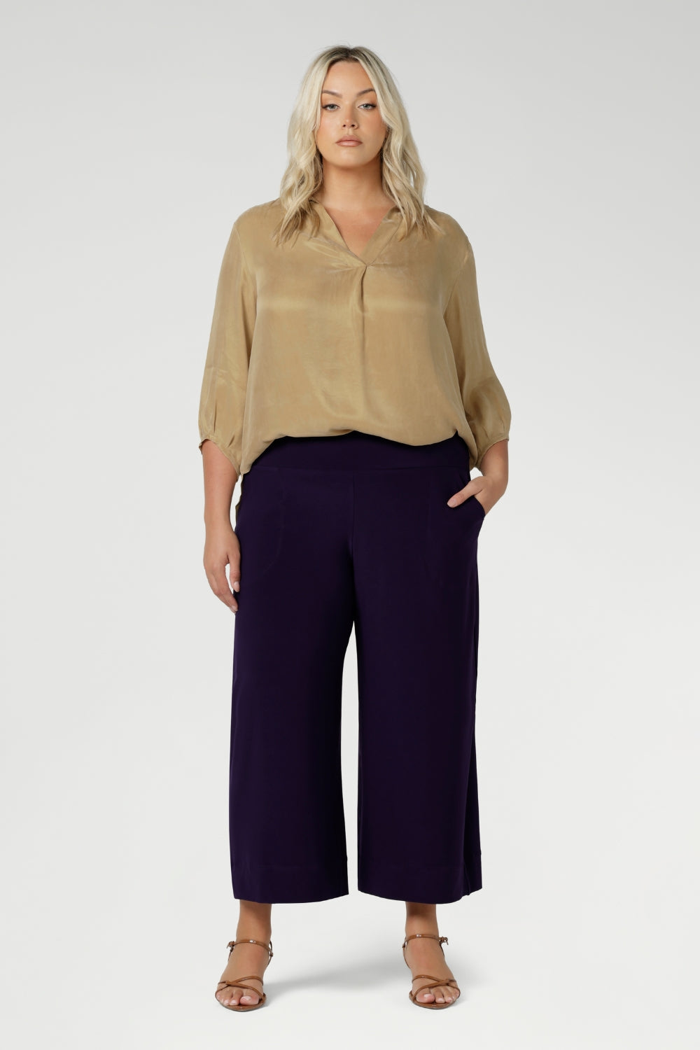 Crafted in Australia, these pull-on pants feature a double-layer waistband that delivers a smooth, flattering fit, ensuring comfort without compromising on style. Available in sizes 8-24 and in both regular and short lengths. Size 18 woman wears her workwear culottes with gold blouse and brown kitten heels.