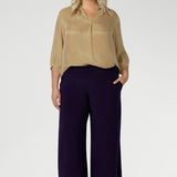 Crafted in Australia, these pull-on pants feature a double-layer waistband that delivers a smooth, flattering fit, ensuring comfort without compromising on style. Available in sizes 8-24 and in both regular and short lengths. Size 18 woman wears her workwear culottes with gold blouse and brown kitten heels.