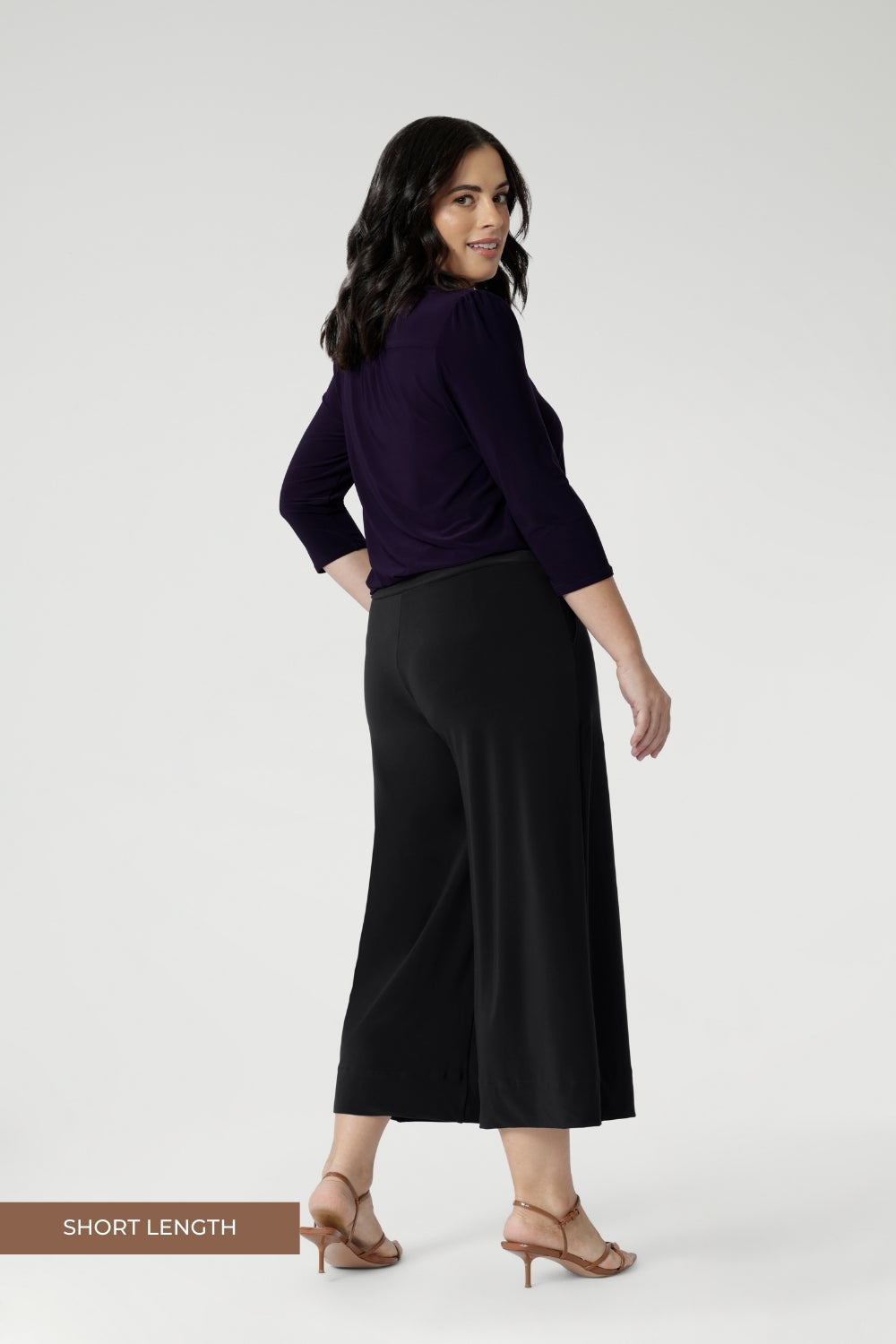 Petite height women wears the short length culottes, paired with amethyst V-neck top and brown kitten heels. The Bradley Culottes in Charcoal come  different leg lengths and are available in sizes 8-24.