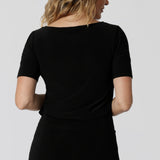 Women's workwear top is worn by size 12 model. An elegant boat neckline across the back is featured on the Ziggy Top. Short sleeved workwear top is close to the arms and is almost elbow length. 