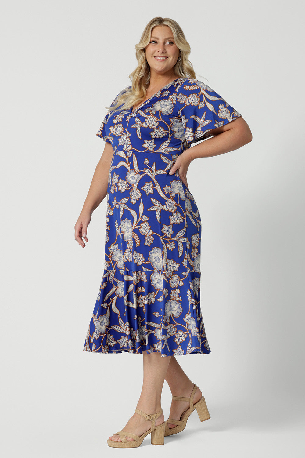 Side view of a midi length dress for plus size women, this twist front jersey dress in size 18 has flutter sleeves and a ruffle hem. A blue dress with floral print, be holiday ready with this travel and cruise wear dress style. Made in Australia by Australian and New Zealand women's clothes brand, Leina & Fleur, shop their petite to plus sizes dresses online.