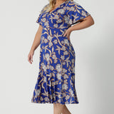 Side view of a midi length dress for plus size women, this twist front jersey dress in size 18 has flutter sleeves and a ruffle hem. A blue dress with floral print, be holiday ready with this travel and cruise wear dress style. Made in Australia by Australian and New Zealand women's clothes brand, Leina & Fleur, shop their petite to plus sizes dresses online.