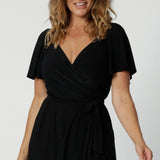 A size 10 midsize woman over 40 is wearing a maxi wrap dress in black. Made in Australia by Australian fashion brand Leina & Fleur in sizes 8 to 24.