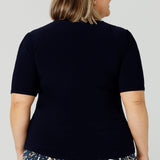 Back view of A petite height size, size 16 woman wears a casual jersey top in navy blue. This Australian-made women's top has short fitted sleeves, a square neckline and and high-low - perfect for weekend casual and travel capsule wardrobes.