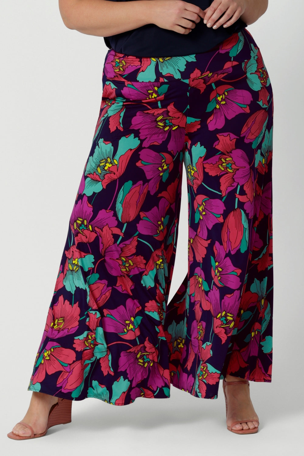 A curvy size 18 woman wears the Caspian Palazzo pant in a bright floral print. In soft and lightweight jersey this pant features side pockets and a flared leg opening. Made in sizes 8 to 24 by Australian fashion brand Leina & Fleur.