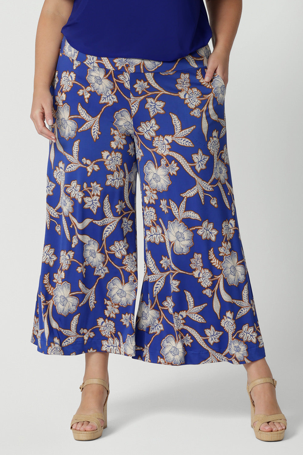 Close up of wide leg pants for summer. Worn by a size 18 , curvy woman, these plus size wide leg pants are in easy care jersey with a blue, caramel and white floral print. Made in Australia by Australian and New Zealand women's clothes label, Leina and Fleur. Shop wide leg pants in petite to plus sizes.