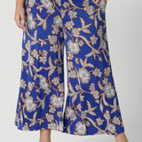 Close up of wide leg pants for summer. Worn by a size 18 , curvy woman, these plus size wide leg pants are in easy care jersey with a blue, caramel and white floral print. Made in Australia by Australian and New Zealand women's clothes label, Leina and Fleur. Shop wide leg pants in petite to plus sizes.