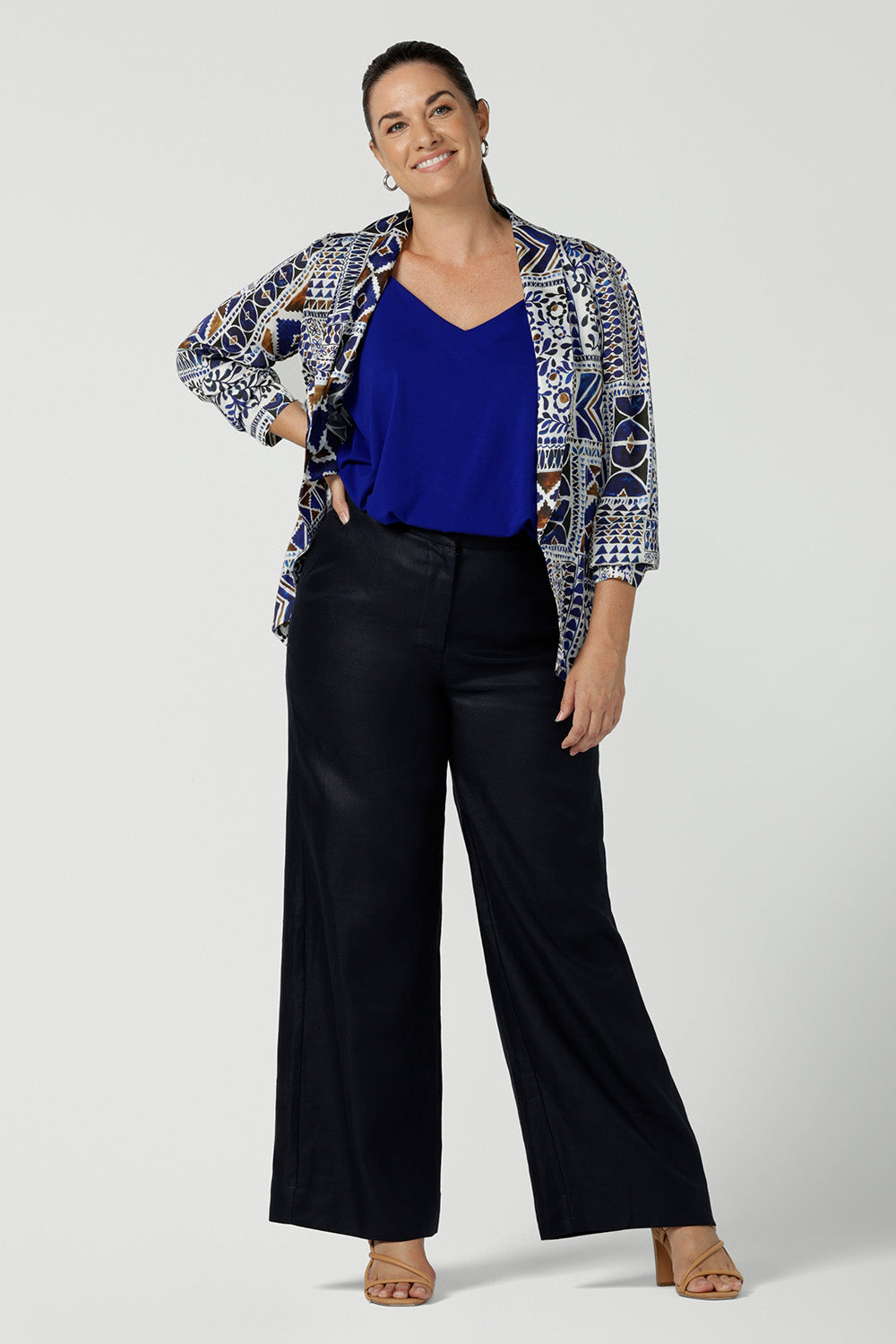 A curvy size 12 woman wears a soft tailoring summer blazer in printed Italian Viscose fabric. A breathable, lightweight women's jacket that's perfect for summer, this Mediterranean-inspired blazer worn with tailored linen pants in midnight blue and cobalt blue bamboo jersey cami  top - all made in Australia by Australian and New Zealand women's clothes brand, Leina & Fleur.