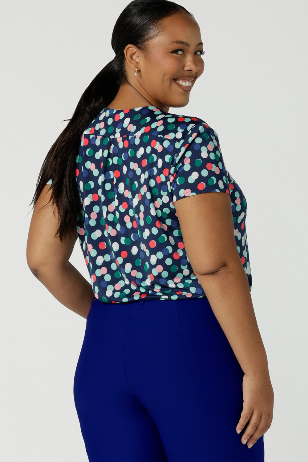 Back view of a size 18 woman wearing a spot print, short sleeve top in slinky jersey fabric. Made in Australia by Australian and New Zealand women's clothing brand, Leina & Fleur, this plus size workwear top  makes a good office wear top as well as a smart casual top. 