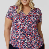 As an off-duty top or a work wear top for women, this V-neck top with tailroed tuck is a comfortable top for women.  A size 18 woman wears a a plus size short sleeve V-neck jersey top in red, pink, white and navy print. Made in Australia top by Australian and New Zealand women's clothes brand, Leina & Fleur, shop their petite to plus size tops online. 