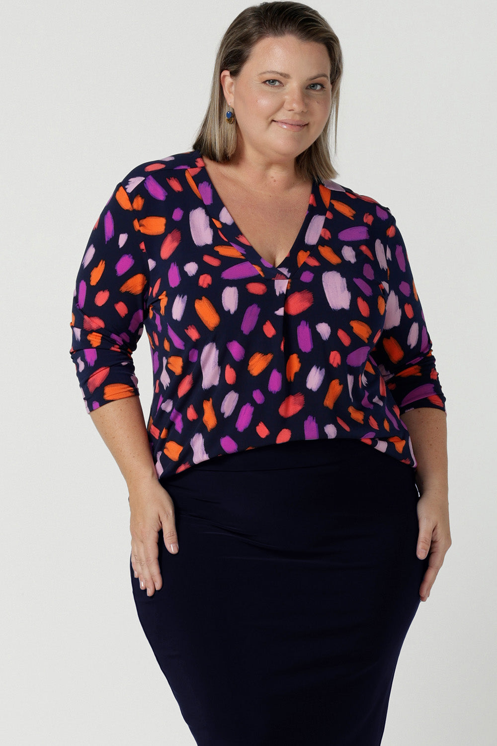 Size 18 curvy woman wears the Jaime top in Palette. A brush stroke inspired abstract print on a navy base with fuchsia, red, orange and pink spots. A v-neck pleat front top great for work to weekend. Comfortable jersey and easy care. Made in Australia for women size 8 - 24.